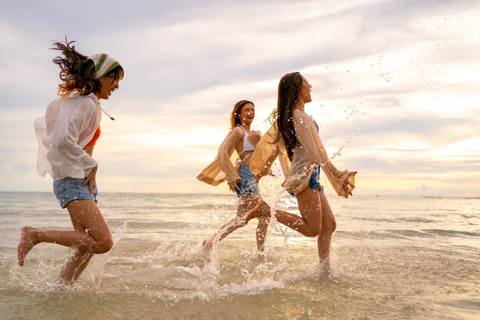 Group of Asian woman friends playing together at the beach.