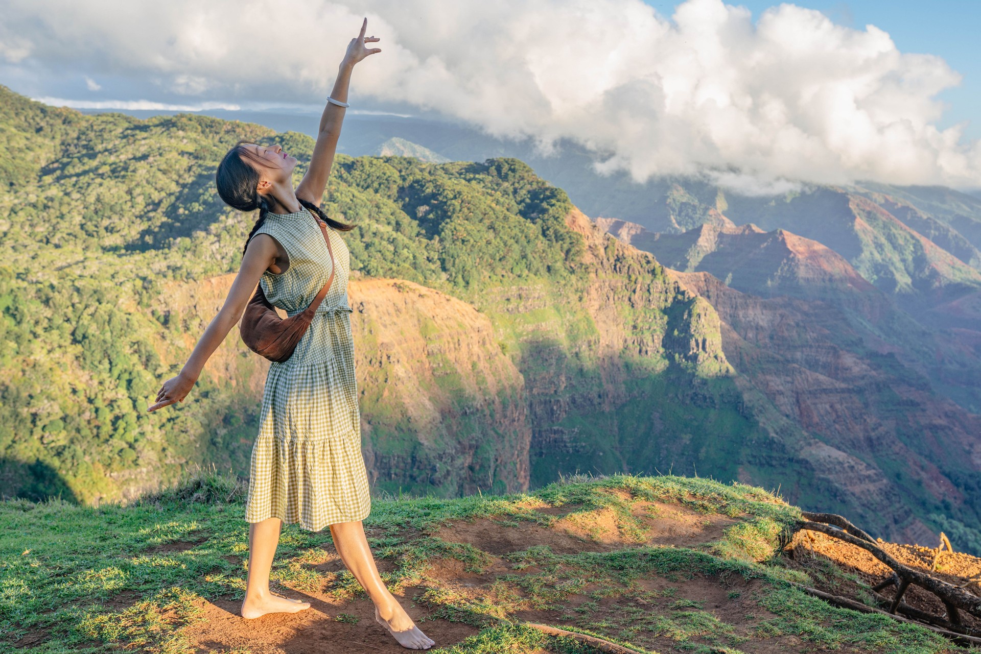 Young woman in a dancing pose on top of the mountain